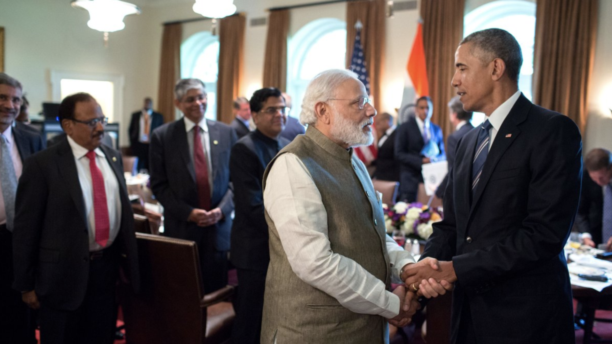 President Barack Obama and Prime Minister Narendra Modi shake hands in front of a room of people