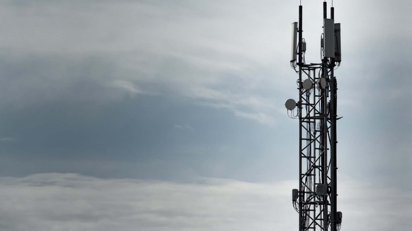 The top of a radio tower is shown in front of a cloudy sky.