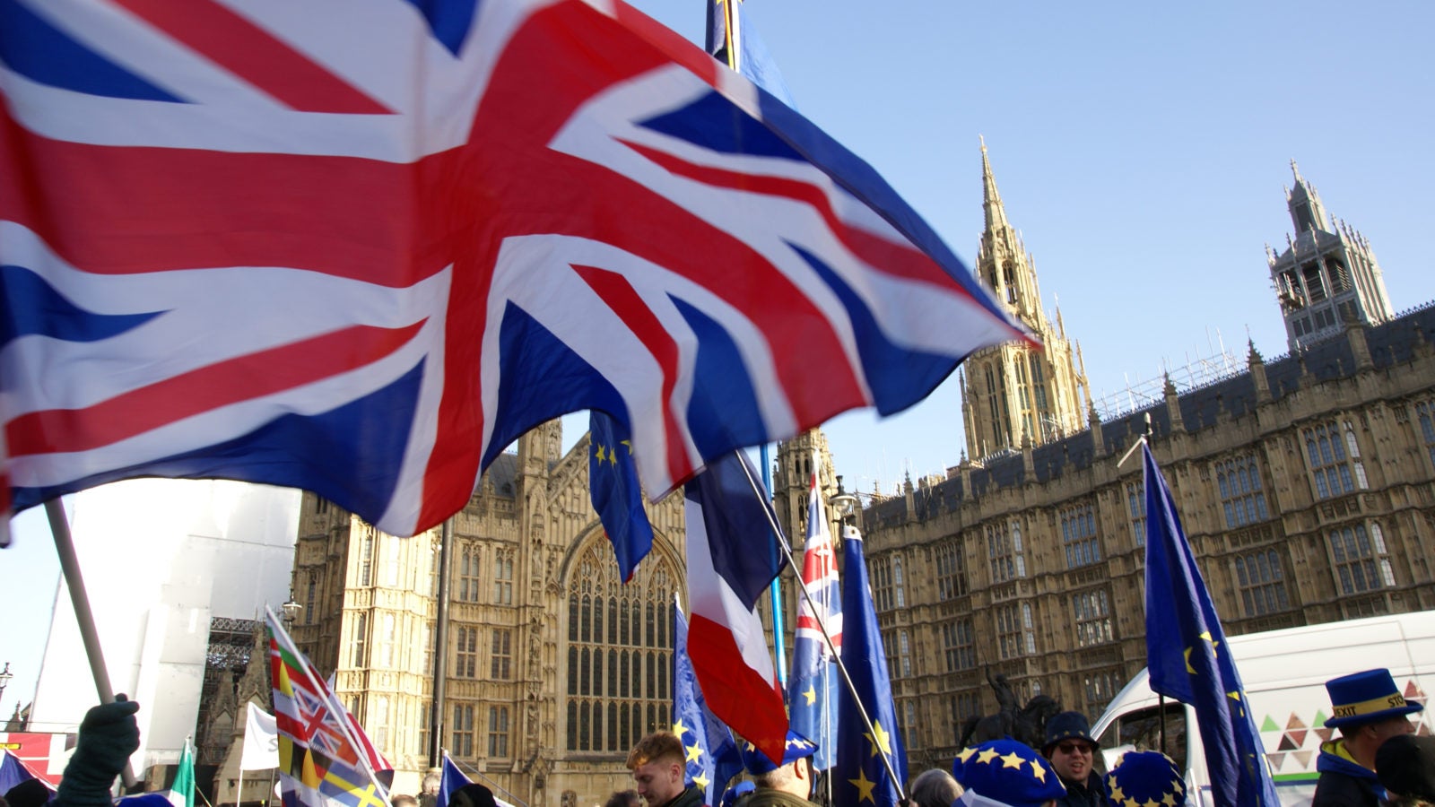 People stand with British and EU flags outside of Westminster Palace.