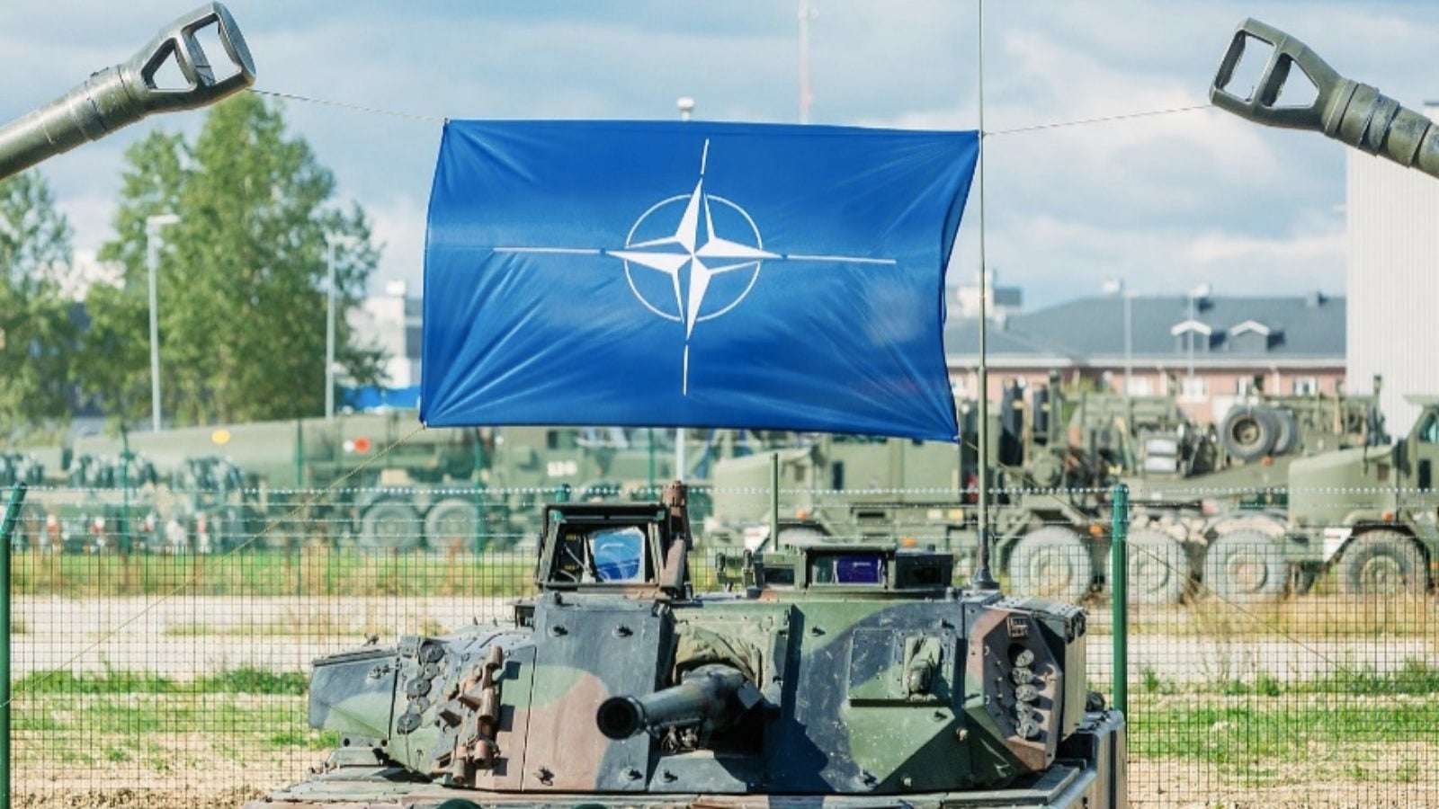 The NATO flag hanging over a tank.