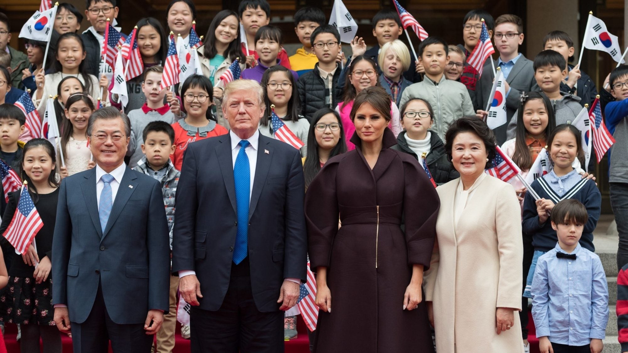 The President of the United States&#039; family standing with the President of South Korea&#039;s family, with American and South Korean flags in the background