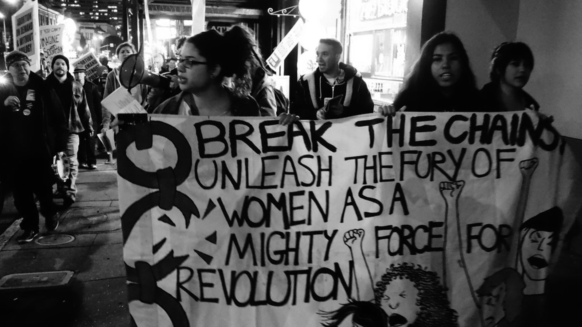 A group of women hold a sign that reads, 