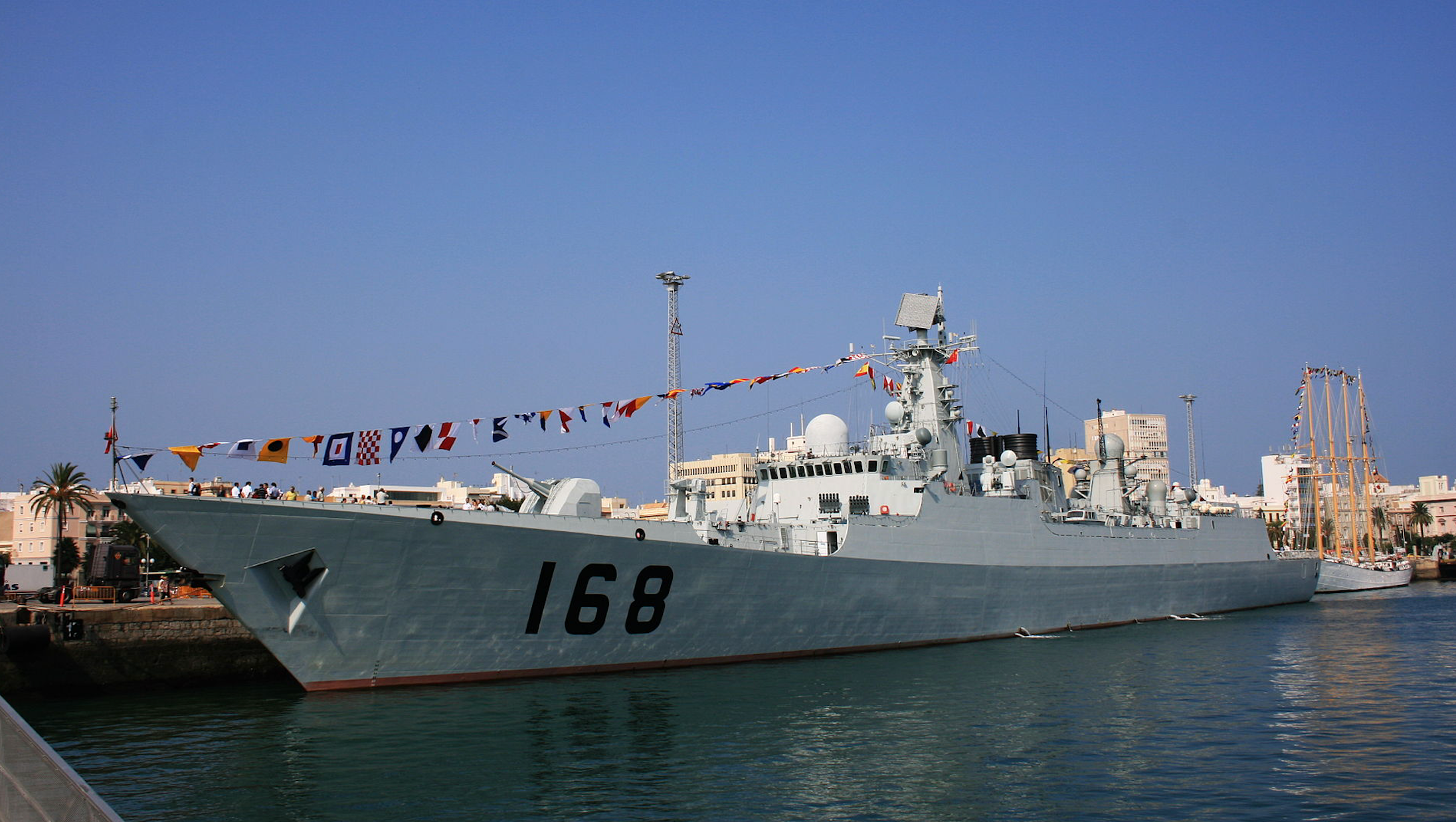 A large Chinese naval boat sits at a dock.