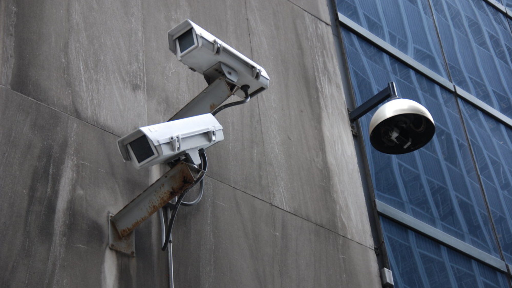 Two video surveillance cameras on the side of a building.