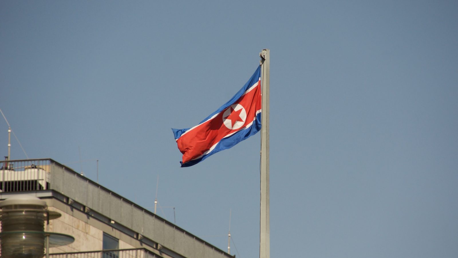 The flag of North Korea flies on a flagpole.