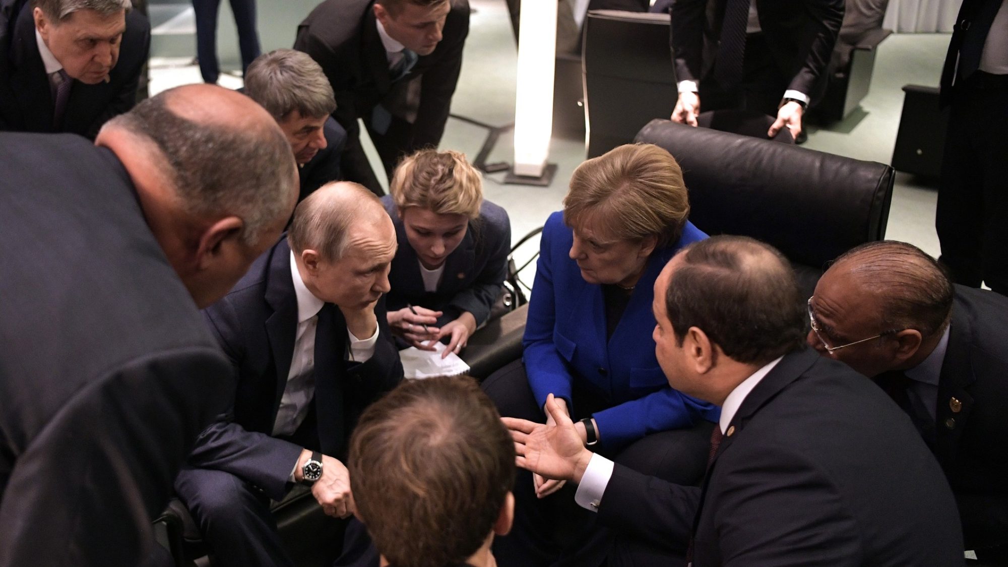 Angela Merkel, Emmanuel Macron, Vladimir Putin, and Abdel Fattah el-Sisi sit with their heads together.