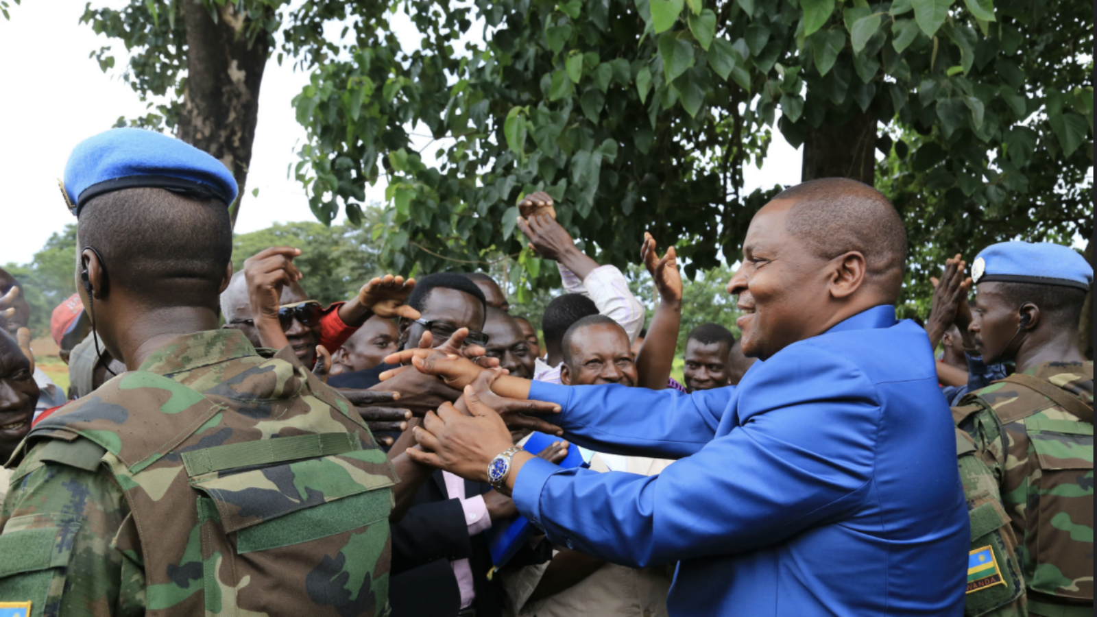 The president of the Central African Republic shakes hands with citizens alongside UN Peacekeepers.