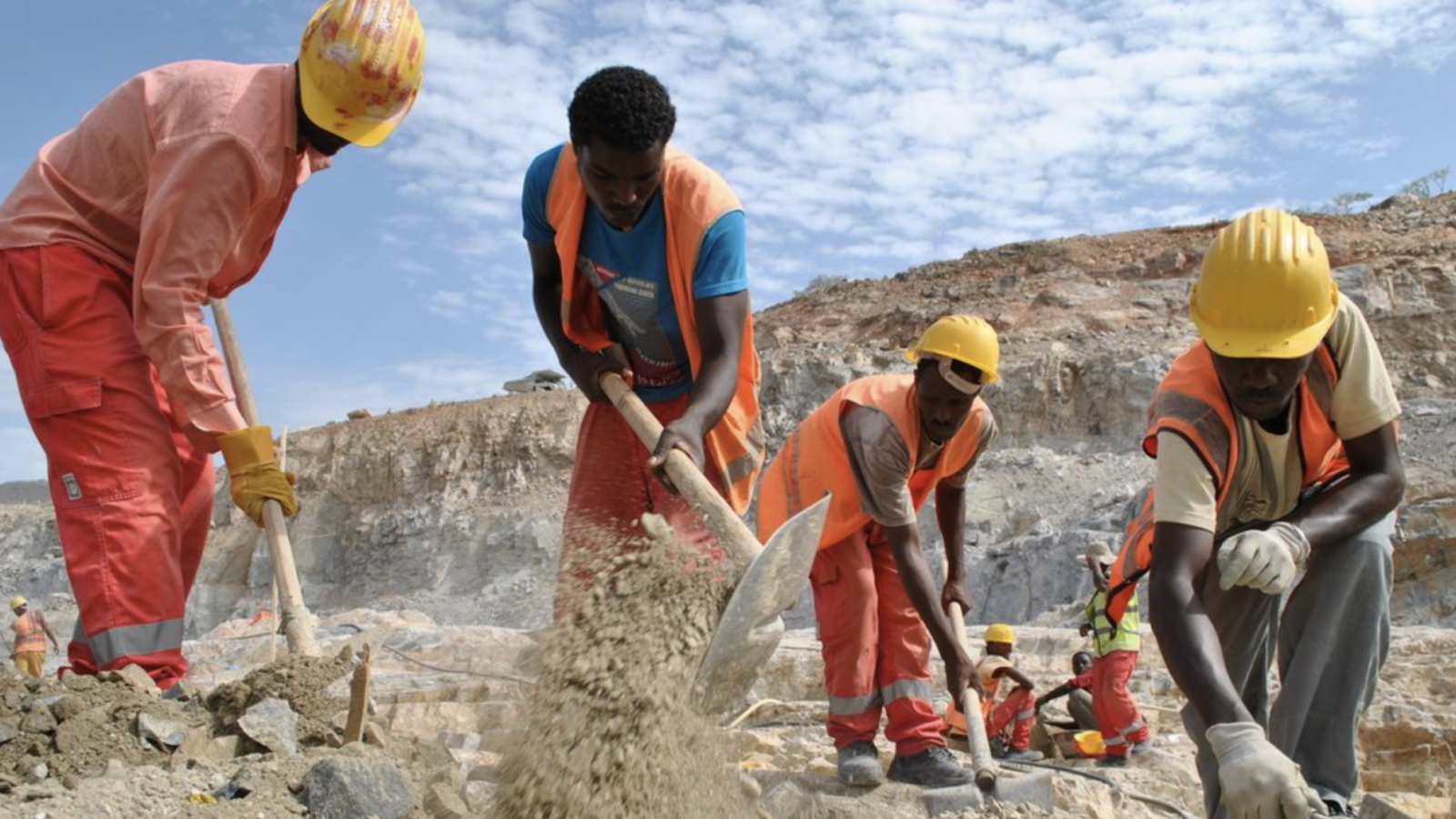 Several men wearing construction gear use tools to break ground for the GERD Dam in Ethiopia.