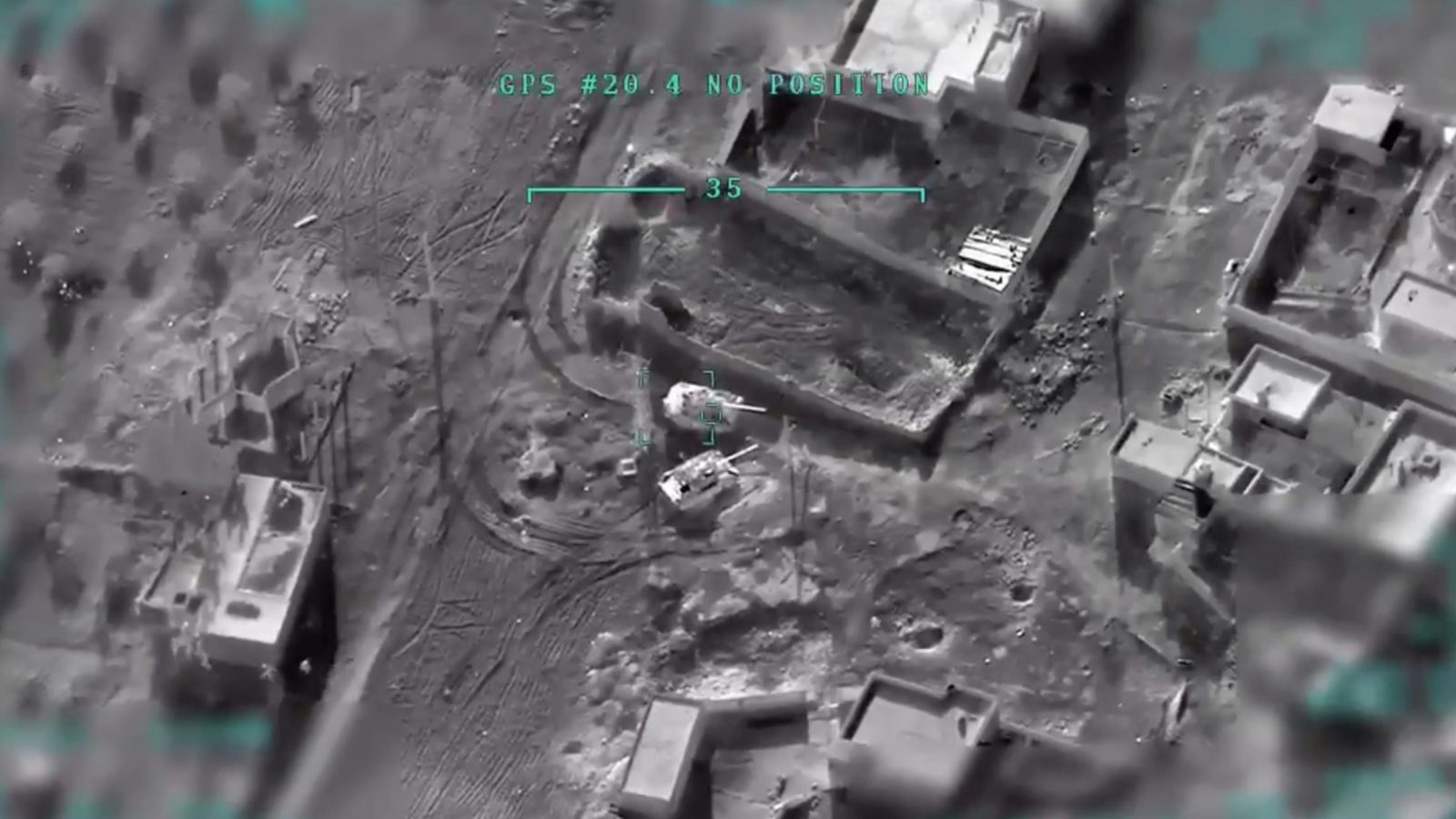 A gray image taken from Turkish drone footage showing buildings, terrain, and tanks from overhead.