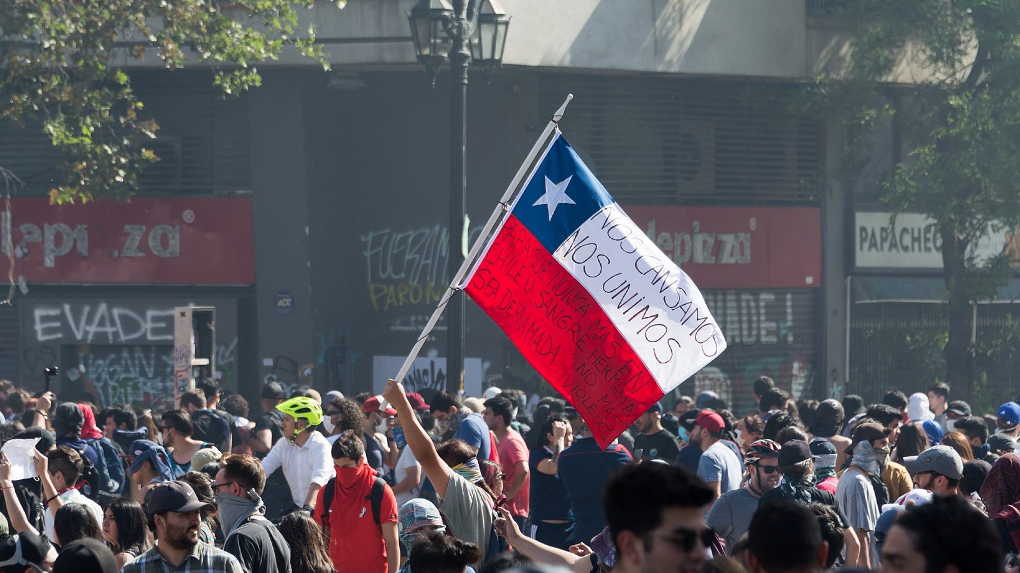 A Chilean flag is raised in the 2019 Protest in Santiago