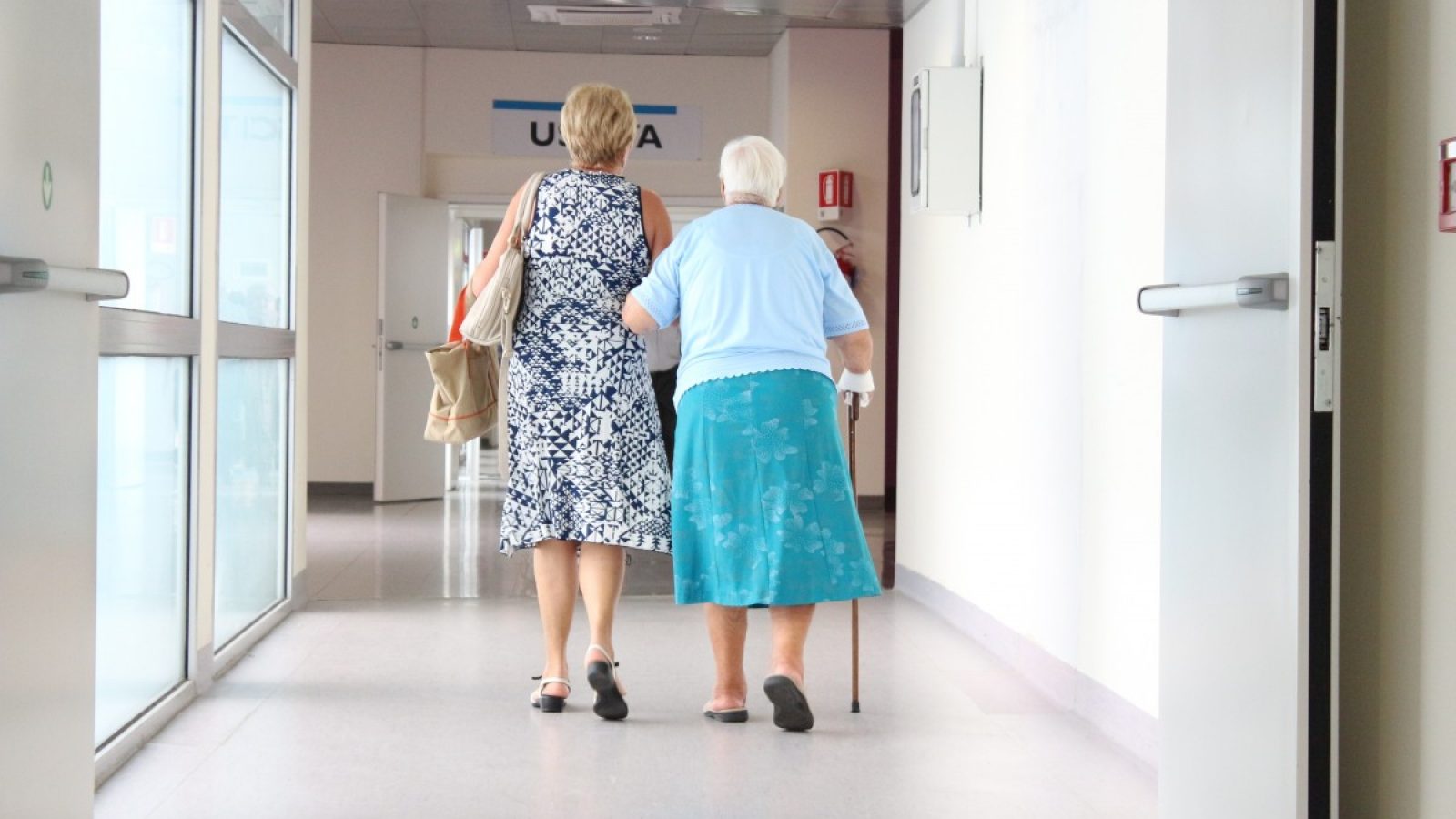 Elderly women walk down a hospital corridor