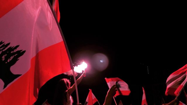 Flare shines light in group of passionate Lebanese protesters. Flags can be seen.
