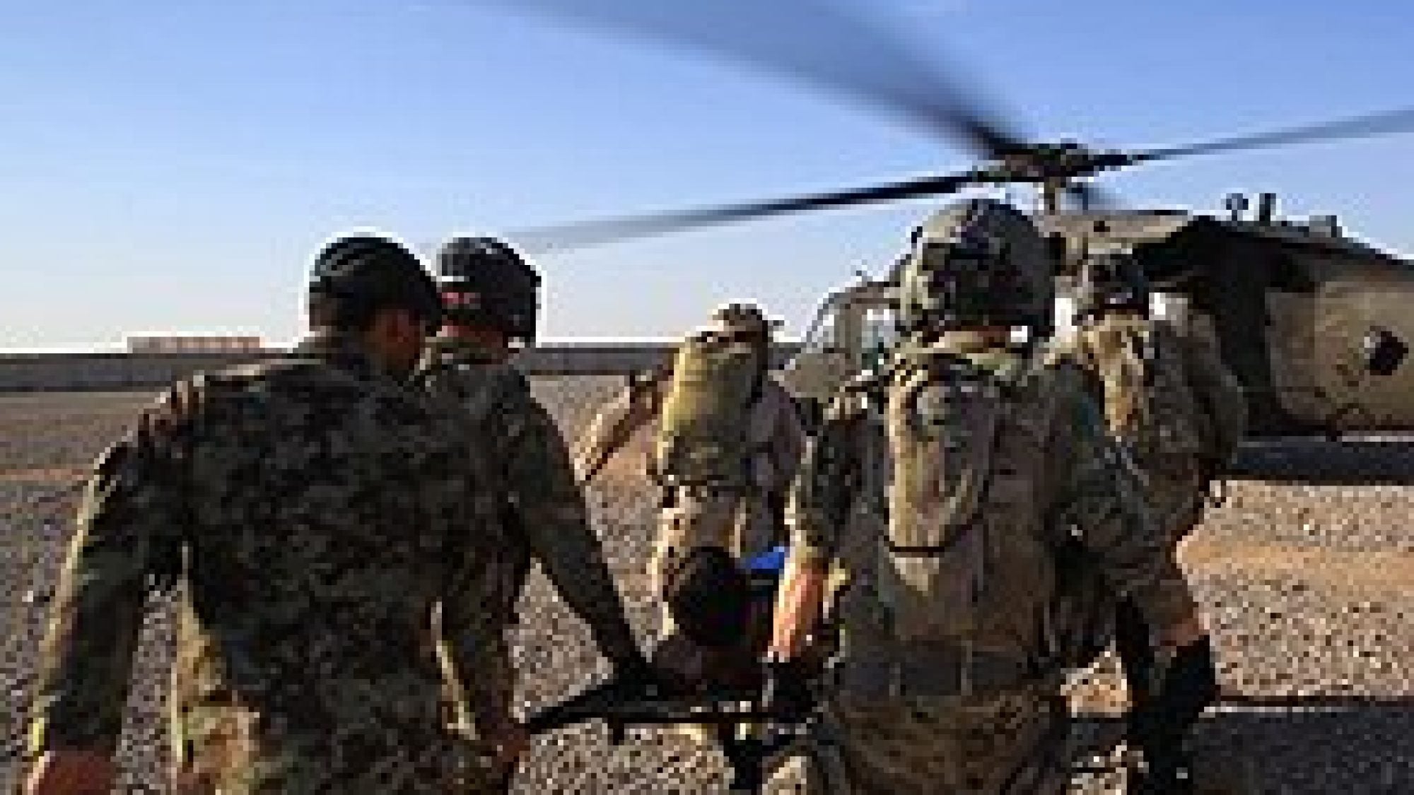 US and Afghan military personnel rush an injured soldier to a helicopter.