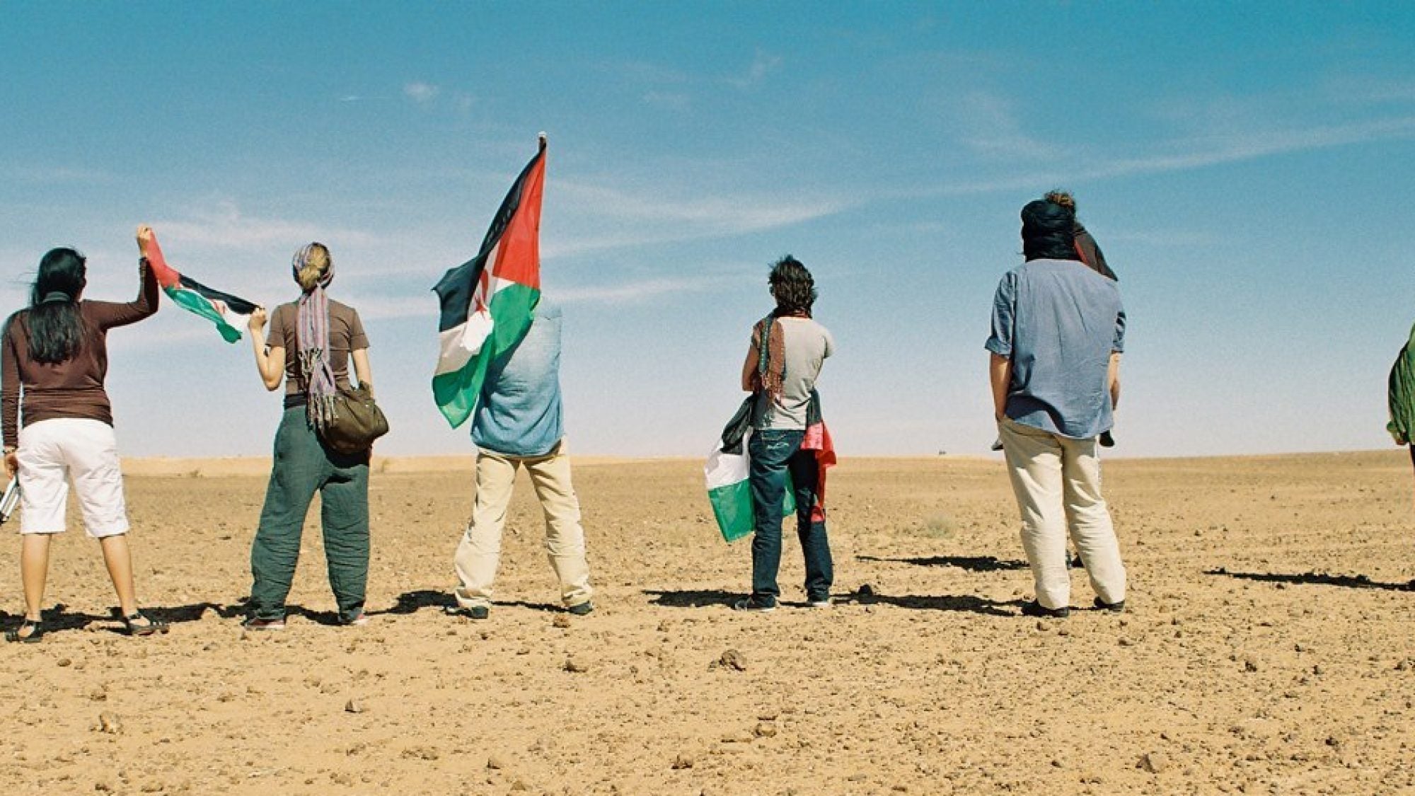 Group of people holding the flag of Western Sahara in a deset