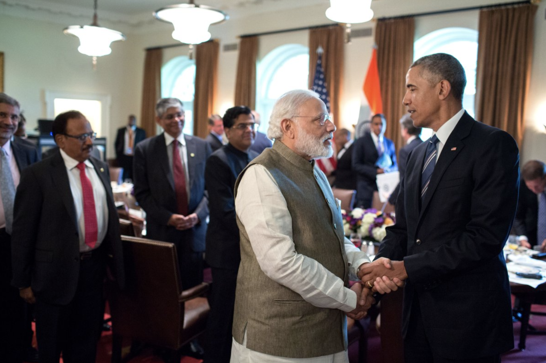 President Barack Obama and Prime Minister Narendra Modi shake hands in front of a room of people