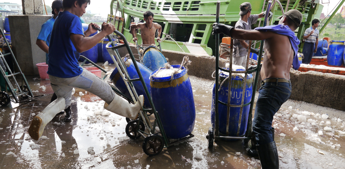 Dockworkers in Thailand load barrels onto a ship.