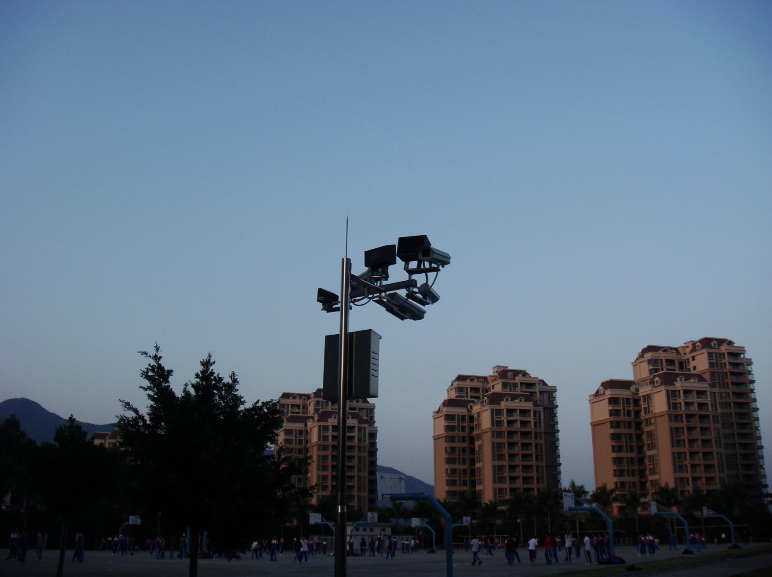 A group of large, modern buildings sit in the shadow, dark and without lights on.