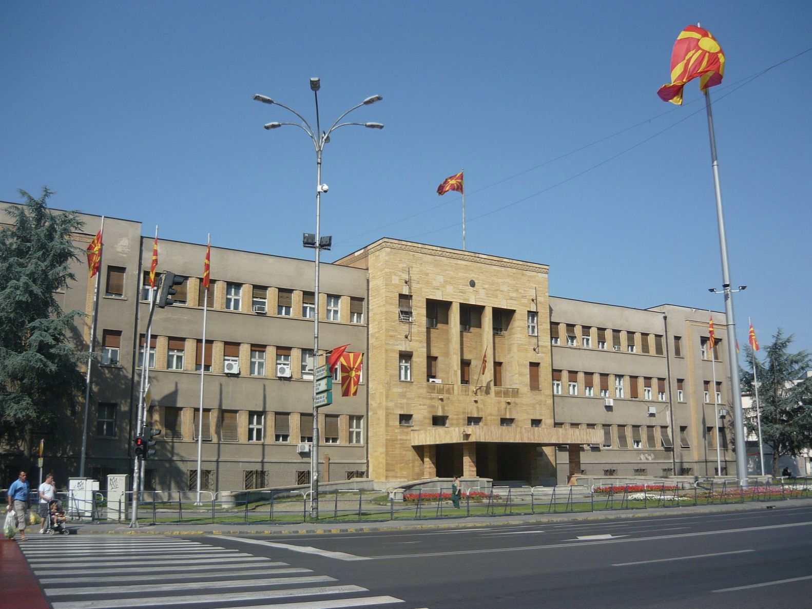 A photo of the front of the Macedonian parliament building, with the Macedonian flag flying out front