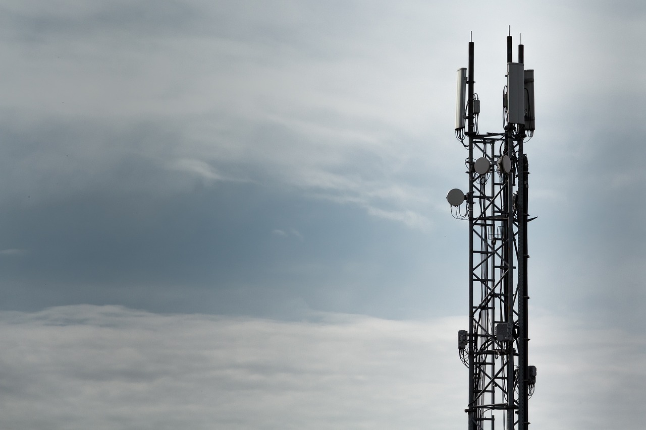 The top of a radio tower is shown in front of a cloudy sky.