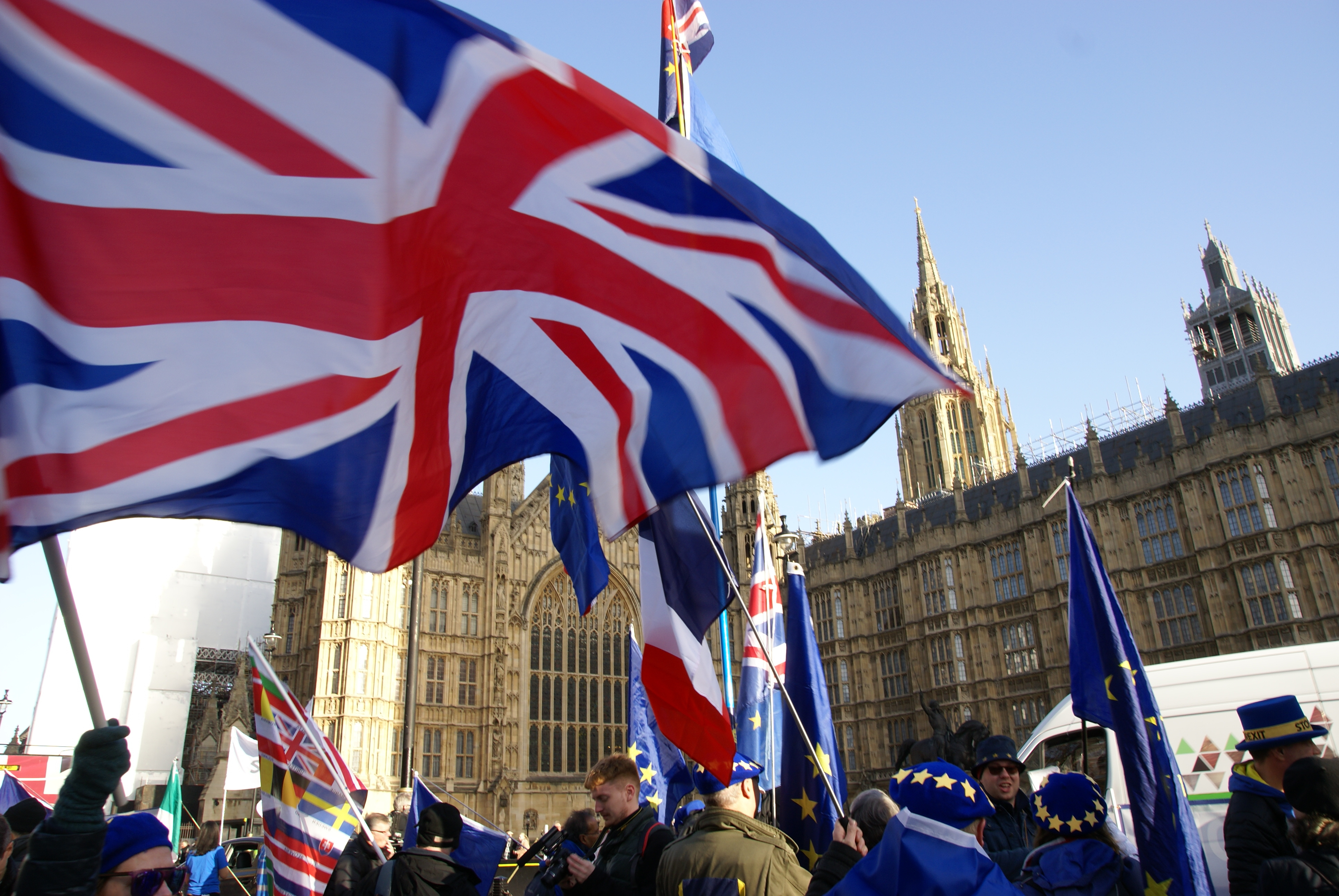 People stand with British and EU flags outside of Westminster Palace.