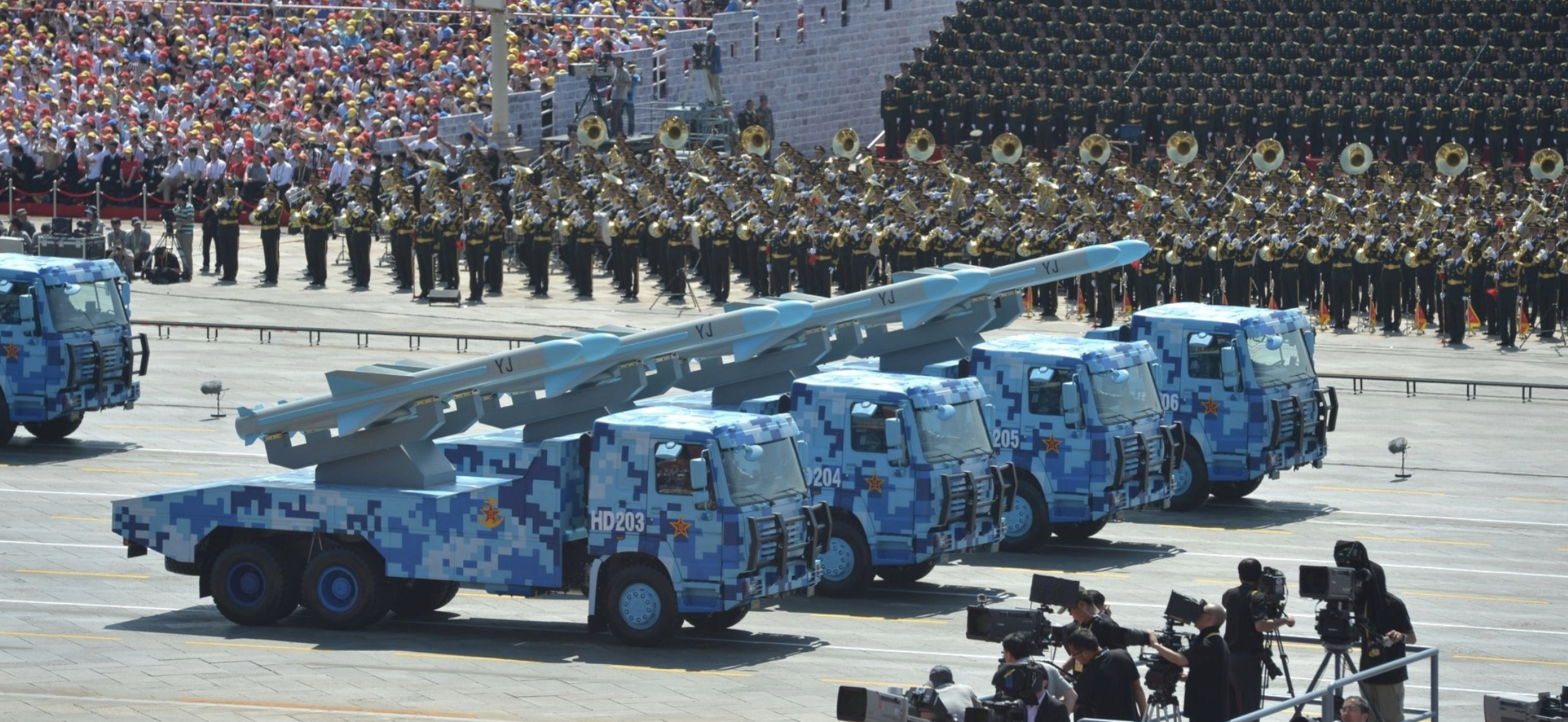 Four trucks carrying missiles marked YJ drive down the road as part of China's 70th National Day parade.