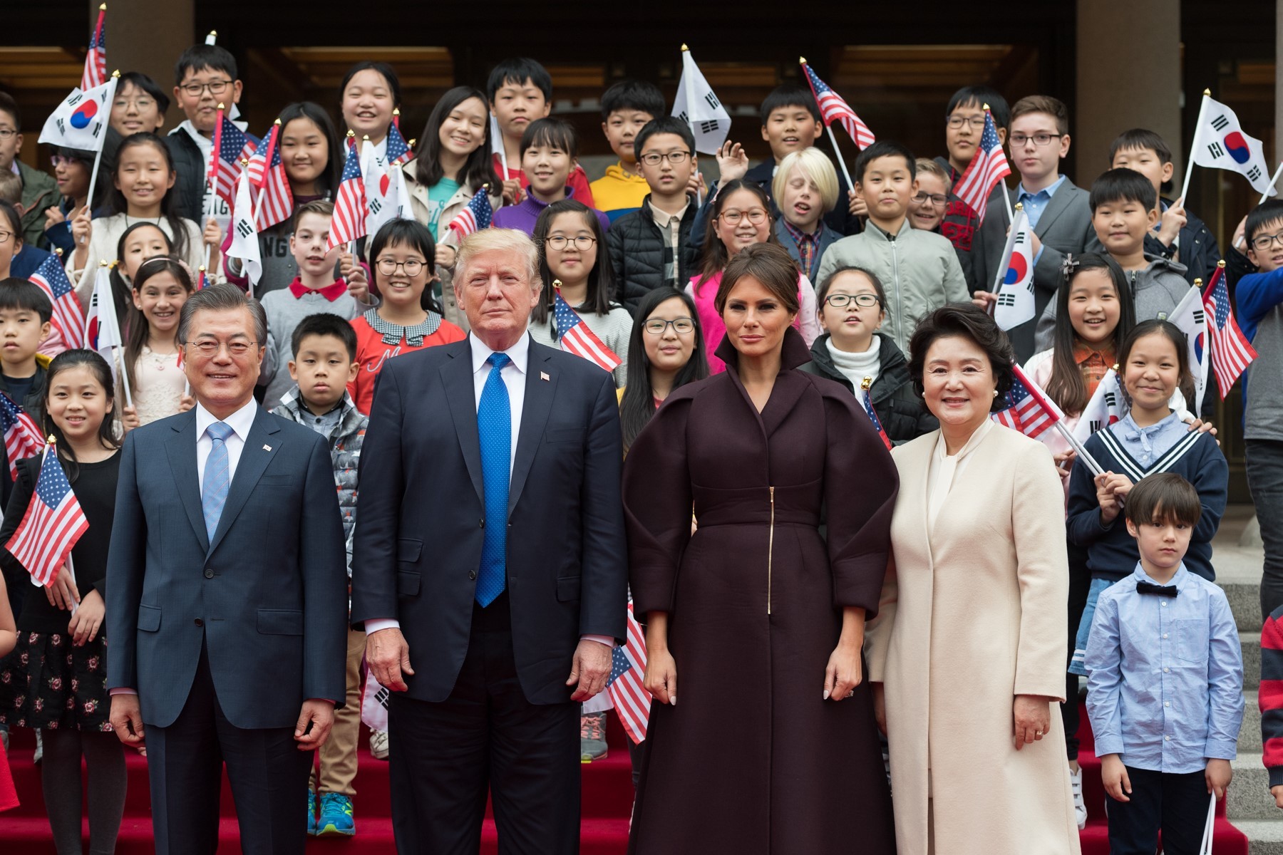 The President of the United States' family standing with the President of South Korea's family, with American and South Korean flags in the background