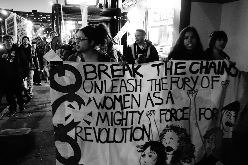A group of women hold a sign that reads,
