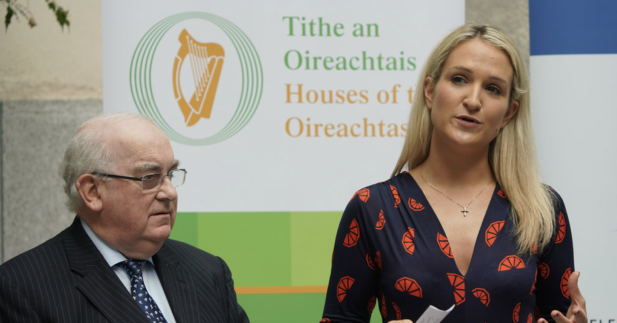 Helen McEntee stands on a stage talking, next to a male Irish official.