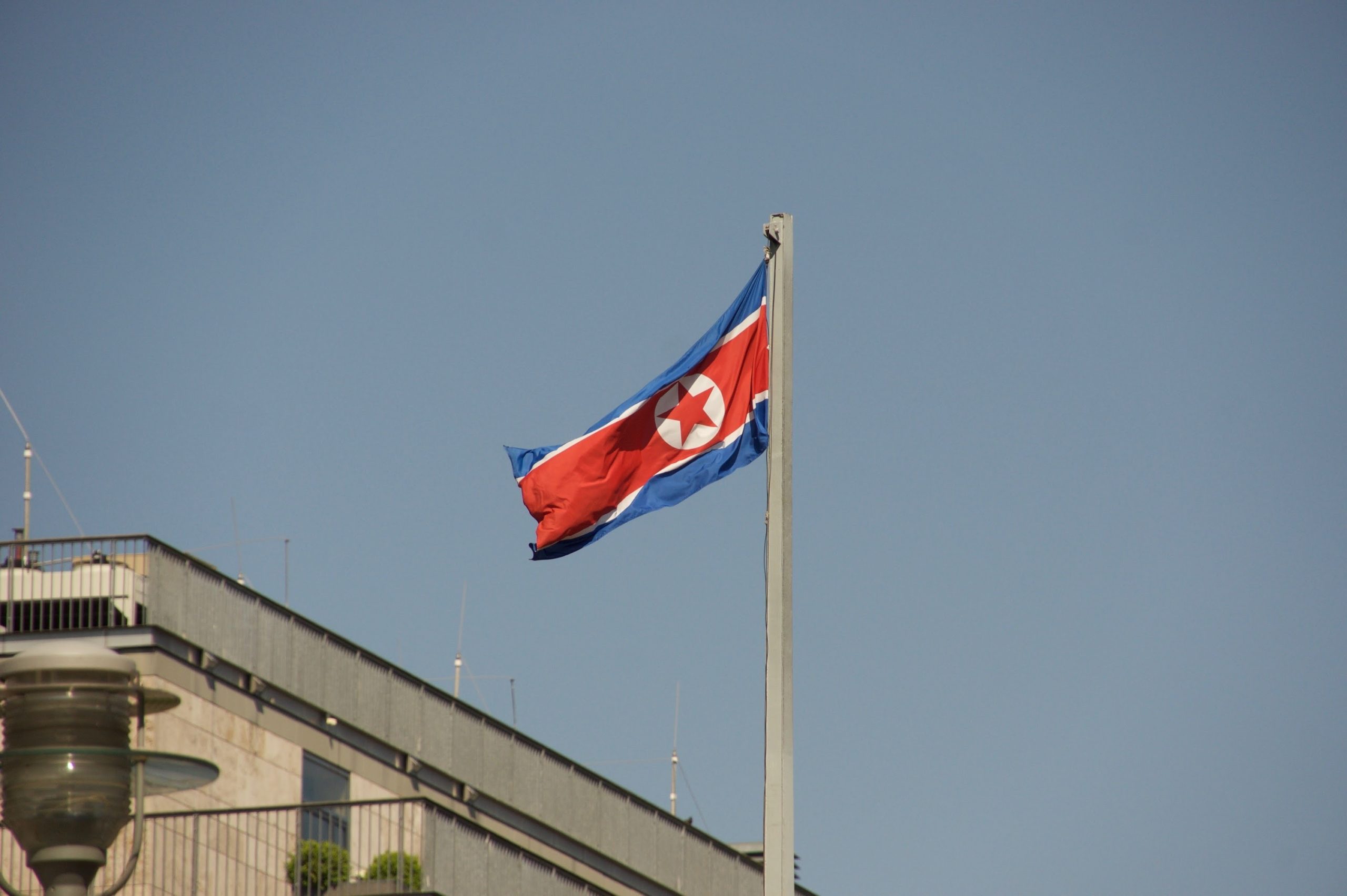 The flag of North Korea flies on a flagpole.