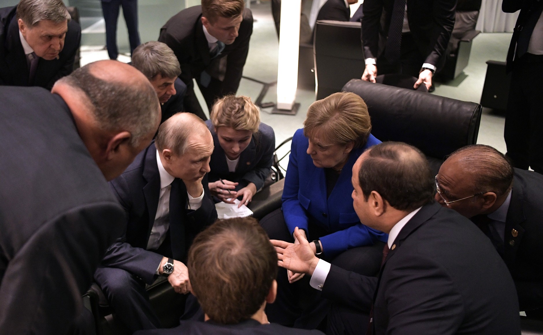 Angela Merkel, Emmanuel Macron, Vladimir Putin, and Abdel Fattah el-Sisi sit with their heads together.