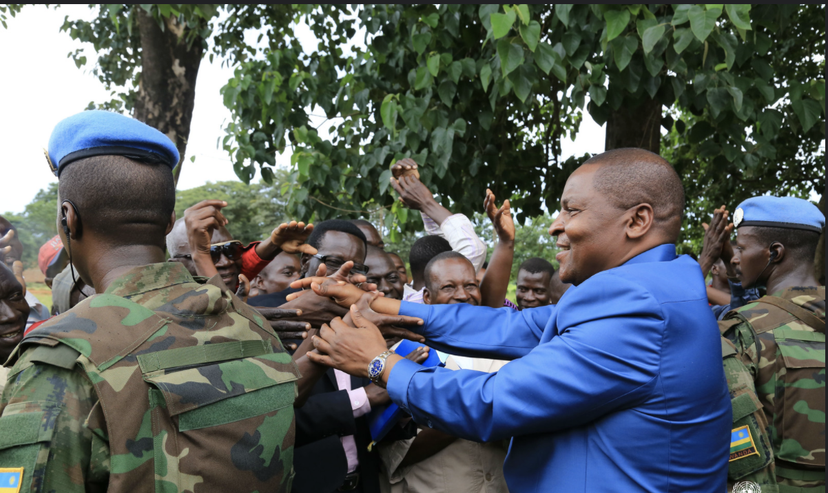 The president of the Central African Republic shakes hands with citizens alongside UN Peacekeepers.