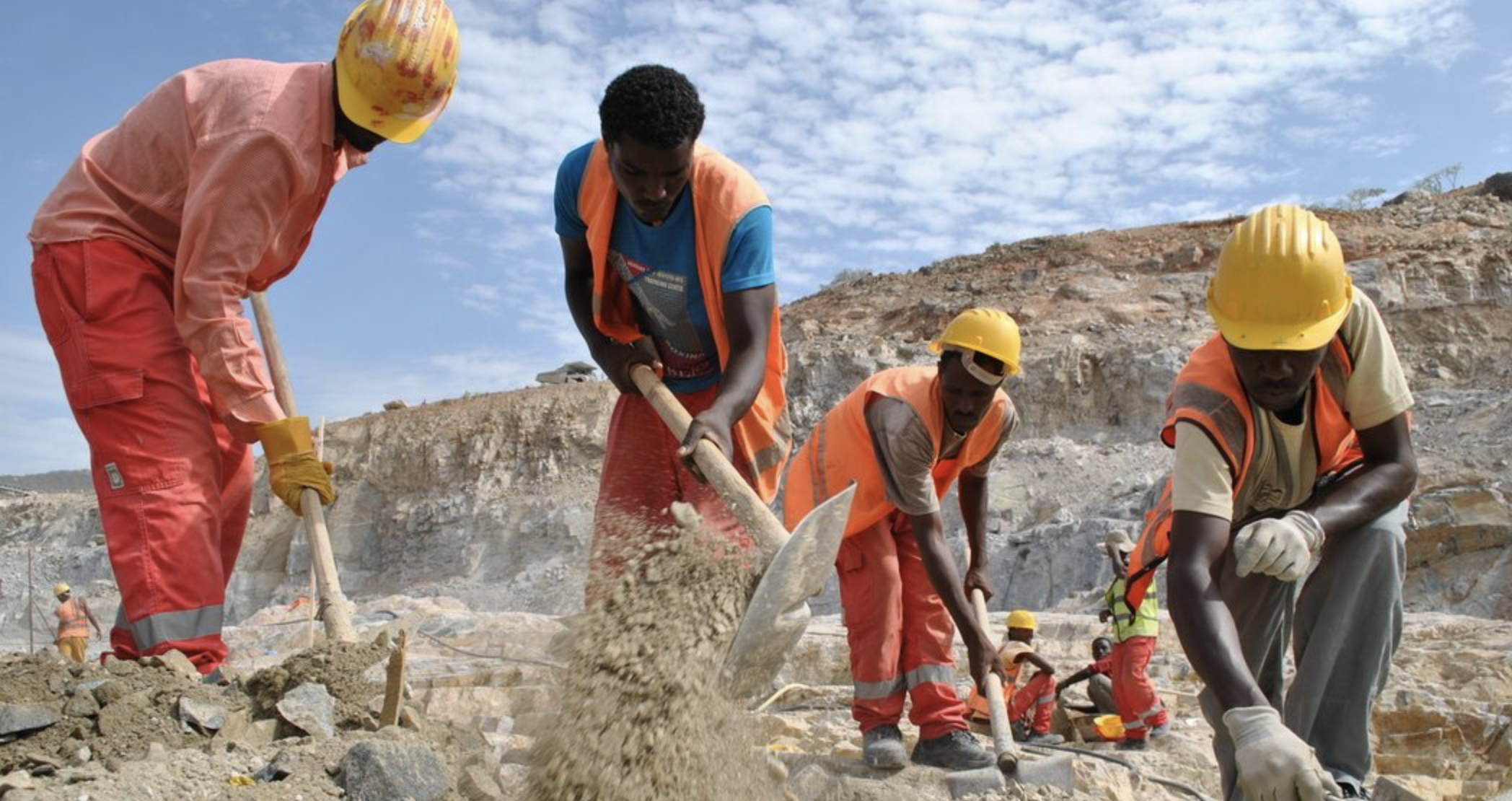 Several men wearing construction gear use tools to break ground for the GERD Dam in Ethiopia.